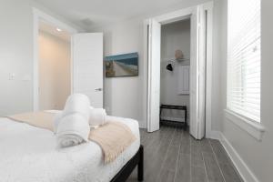 a white bedroom with a bed and a window at Be a Nomad - Newly renovated 4 blocks to beach in Jacksonville Beach