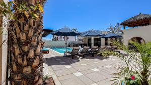 a patio with chairs and umbrellas next to a pool at Paz del Mar Room 06 Perico in Las Conchas