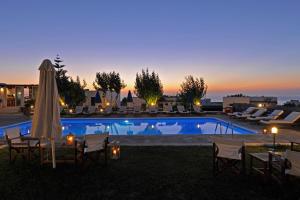 a pool with chairs and umbrellas at dusk at Fragoulis Village in Parasporos