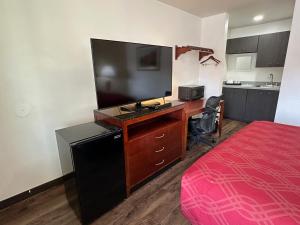 a room with a bed and a desk with a flat screen tv at Desert Sands Inn & Suites in Albuquerque