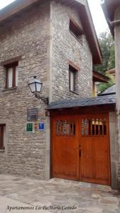 a stone building with a wooden garage door at Tía María in Cerredo