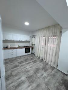 a kitchen with white cabinets and a tile floor at Apartament Valcea in Râmnicu Vâlcea