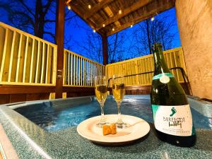 Una botella de champán y dos copas de vino. en Charming Cabin, Seasonal Decor & Pool, 3min to Pkwy, Grill, GameRoom, Wifi & Workstation, Sleeps 14, en Pigeon Forge
