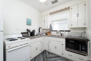 eine weiße Küche mit einem Herd und einer Mikrowelle in der Unterkunft Be a Nomad - Charming bch cottage - 3 blks to bch in Jacksonville Beach