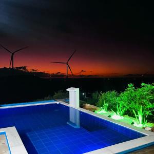 ein Schwimmbad in der Nacht mit Windmühlen im Hintergrund in der Unterkunft Margarida 03 in Monte das Gameleiras