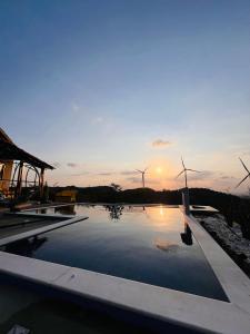 einem Pool mit Windmühlen und dem Sonnenuntergang im Hintergrund in der Unterkunft Margarida 03 in Monte das Gameleiras