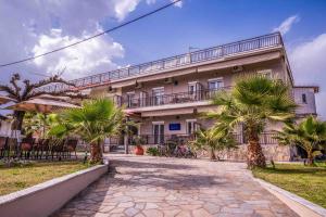 a building with palm trees in front of it at Ador El Mar in Leptokarya