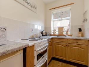 eine Küche mit einem weißen Herd oberer Ofen neben einem Fenster in der Unterkunft Holiday Home Foxglove cottage by Interhome in Straiton