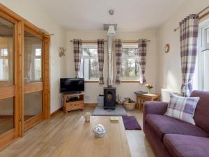 ein Wohnzimmer mit Sofa und Fernseher in der Unterkunft Holiday Home Foxglove cottage by Interhome in Straiton