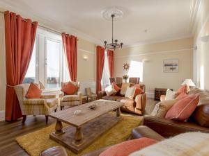 a living room with red curtains and a table at Holiday Home Portpatrick House by Interhome in Portpatrick +25 photos