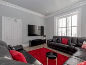 a living room with a black couch and a red rug at Holiday Home Portpatrick House by Interhome in Portpatrick