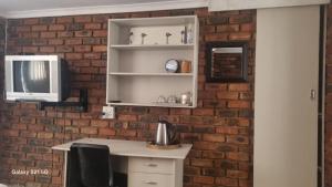 una cucina con muro di mattoni e una scrivania con forno a microonde di Eagles Rest a Klerksdorp Altre 37 foto