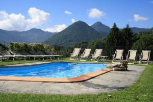 a swimming pool with lounge chairs and mountains in the background at Hotel La Torre in Castiglione dʼIntelvi