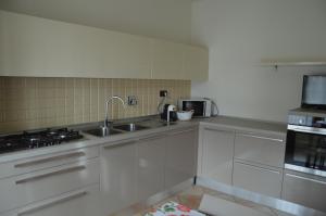 a white kitchen with a sink and a microwave at Casa Emma in Torre Pellice +21 photos