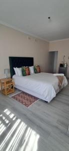 a bedroom with a large white bed with a rug at 04 at Beaumont in King Williamʼs Town +8 photos