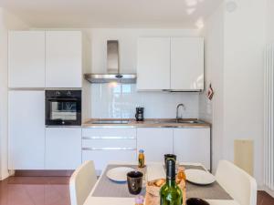 a kitchen with white cabinets and a table with a bottle of wine at Apartment Alborella by Interhome in Domaso +15 photos