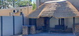 a house with a thatched roof with chairs and a table at 04 at Beaumont in King Williamʼs Town