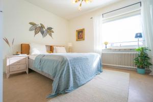 a bedroom with a bed with a blue blanket and a window at HaHa Gothenburg City Apt for 2 in Gothenburg