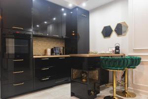 a kitchen with black cabinets and a green stool at Hanza Tower - Golden Heaven Apartment in Szczecin +18 photos