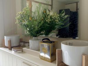 Un mostrador de baño con jarrones y flores. en Tinsmiths House, en Aylsham