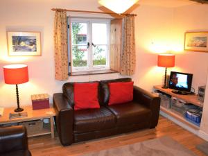 a living room with a leather couch and a window at Foxhole in Threlkeld
