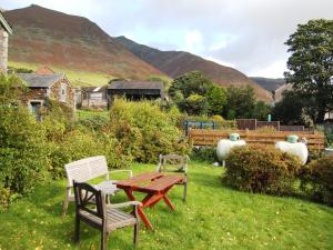 a picnic table and chairs in a yard with mountains at Foxhole in Threlkeld +3 photos