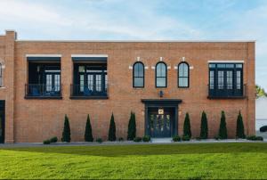 a red brick building with a green lawn at The Purple Martin - The Odd Bird in Louisville