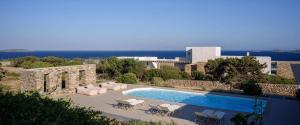una piscina con sillas, un edificio y el océano en Niovi Antiparos Luxury Villas, en Soros