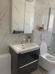 a white bathroom with a sink and a toilet at Appartement Moderne in Saint-Cergues