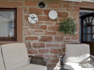 two chairs and clocks on a brick wall at The Milking Parlour - Uk30866 in St Bees