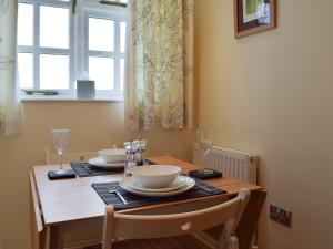a dining room table with two chairs and a table with glasses at Valeview Cottage in Great Malvern