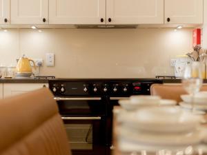 eine Küche mit einem Backofen und einem Tisch mit Geschirr in der Unterkunft Holiday Home Balbeg Cottage by Interhome in Straiton + 22 Fotos