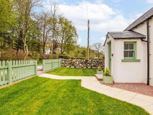einen Hinterhof mit einem Zaun und einem Garten mit grünem Gras in der Unterkunft Holiday Home Balbeg Cottage by Interhome in Straiton