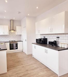 a white kitchen with white cabinets and a wooden floor at Hidden pearl in Gorleston-on-Sea +13 photos