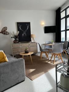 a living room with a couch and tables and a tv at Nid cosy avec vue montagne au coeur de saint lary in Saint-Lary-Soulan