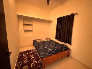 a small bedroom with a bed and a black curtain at TVK Grands 7 - Premium One Bedroom Apartment in Coimbatore