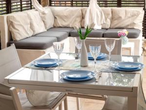 una mesa con platos y vasos y un sofá en Apartment La Veranda di Mirko by Interhome, en Porto Rotondo