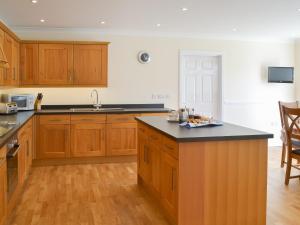 a kitchen with wooden cabinets and a black counter top at Driftwood in Port Isaac
