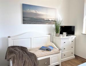 a bedroom with a white bed with a dresser and a tv at Frida SPO Ferienwohnung Nordsee mit Hund in Böhl