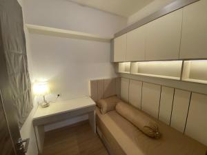 a small room with a bed and a table with a lamp at Sky House BSD in Samporo