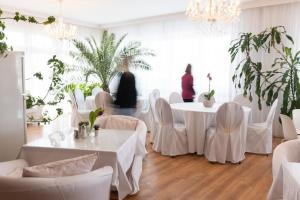 a room with white tables and chairs and plants at HOTEL MARIA in Gramatneusiedl