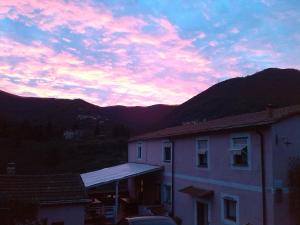 um pôr-do-sol sobre uma casa com montanhas ao fundo em Agriturismo Locanda del Papa em La Spezia