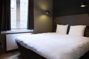 a large white bed in a room with a window at The Duke Boutique Apartments in Den Bosch