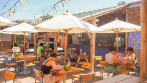 people sitting at tables in a restaurant under umbrellas at Viajero Paracas Hostel in Paracas