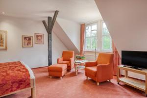 a bedroom with a bed and two chairs and a television at Landhotel Waldseiter Hof in Bad Bentheim