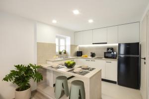 a kitchen with white cabinets and a black refrigerator at Victoria's Gem - Apartment in the Heart of Corfu Old Town in Corfu