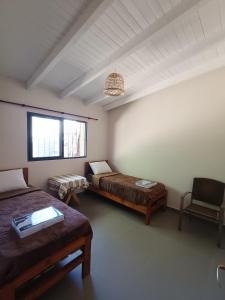 a room with two beds and a chair in it at Corazón de Maimara in Maimará