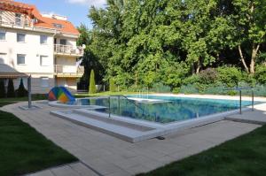 a swimming pool in a yard next to a building at Luxory & Spa Apartman in Hajdúszoboszló