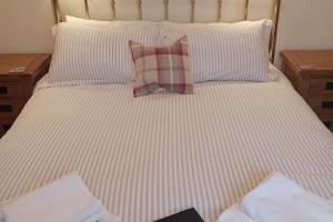 a bed with a striped sheets and a pillow on it at The Snug a cosy, quirky detached cottage with sea views in Innellan