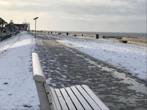 a bench sitting on the beach in the snow at Nice holiday home near the centre in Duhnen +8 photos